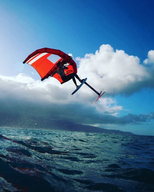 Wing foiler riding above the water on Maui